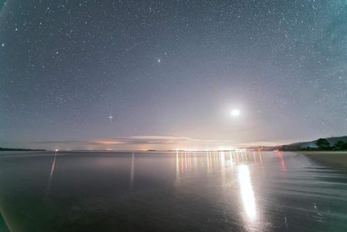 a night view of a lake with the moon and stars at Cabañas Kompatzki in Ancud