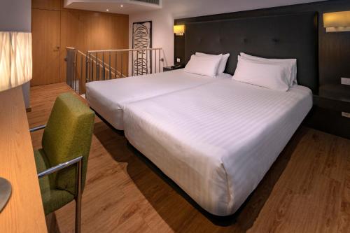 sypialnia z dużym białym łóżkiem i krzesłem w obiekcie Apartments Playa de Castelldefels w mieście Castelldefels