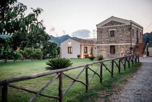 una casa de piedra con una valla delante de ella en Valle degli Agrumi, en San Pier Niceto