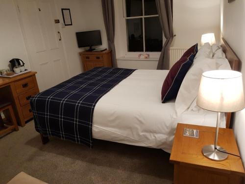 a bedroom with a bed and a lamp and a window at Ty Helyg Guest House in Brecon