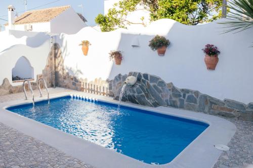una piscina con cascada frente a una casa blanca en Casa Lola, en Zahora