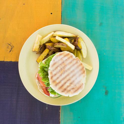 a plate of food with a sandwich and french fries at The Upcycled Hostel Huacachina in Ica