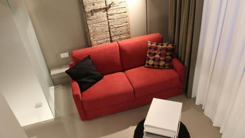 a red couch with two pillows on it in a room at Serre Alte Landscape Luxury Rooms in Matelica