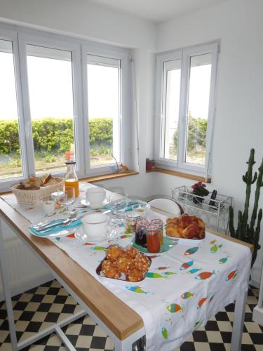 a table with food on it in a kitchen with windows at "Lumière du Cap" vue mer B&B à la VILLA PLEIN VENT in Barneville-Carteret