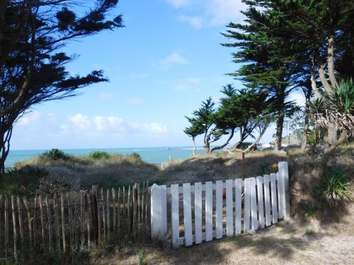 a white fence on a beach with the ocean in the background at "Lumière du Cap" vue mer B&B à la VILLA PLEIN VENT in Barneville-Carteret