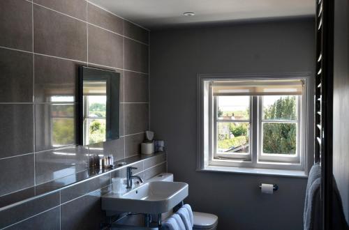 a bathroom with a sink and two windows at Crown and Castle in Orford