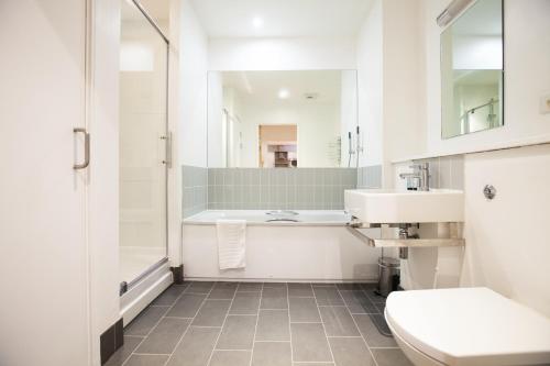 a bathroom with a tub and a toilet and a sink at Urban Living's - The Burley Luxury City Apartment in Oxford