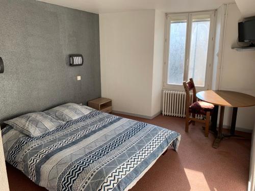 a bedroom with a bed and a table and a window at L'Escale in Longeau