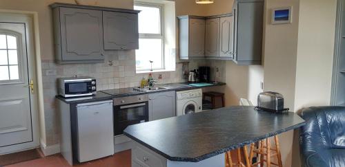 een keuken met een wastafel en een aanrecht bij Jacks' Coastguard Cottage Vacation home in Glenbeigh