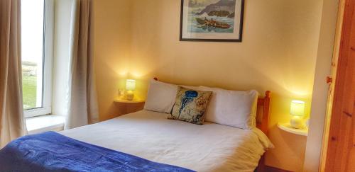 um quarto com uma cama com 2 candeeiros e uma janela em Jacks' Coastguard Cottage Vacation home em Glenbeigh