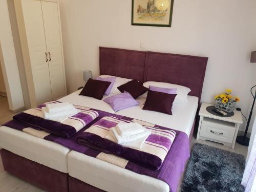 a bedroom with a large bed with purple and white pillows at Ana Tudor Apartments in Hvar