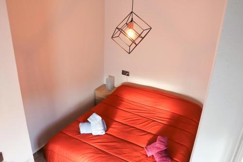 Cama roja en una habitación pequeña con lámpara en Corona 101, en Nerja
