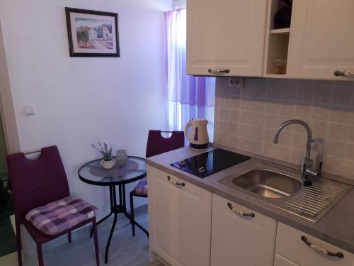 een kleine keuken met een wastafel en een tafel bij Ana Tudor Apartments in Hvar