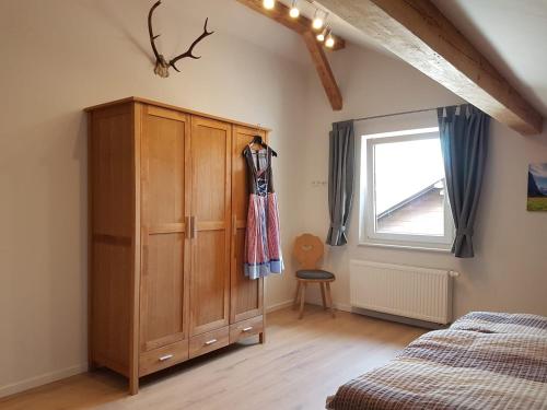 - une chambre avec une armoire en bois, un lit et une fenêtre dans l'établissement FeWo "Im Städt´le" Immenstadt, à Immenstadt