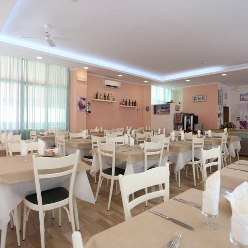 a dining room with white tables and white chairs at Hotel Madrid in Cattolica