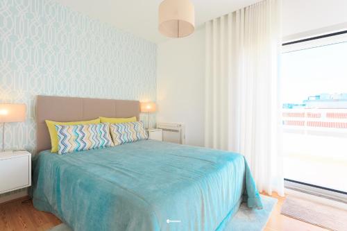 a bedroom with a bed and a large window at Nazare Marisol Praia in Nazaré