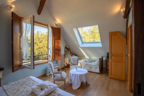 a bedroom with two beds and a table and windows at Le Colombier de Hanches - Teritoria in Hanches