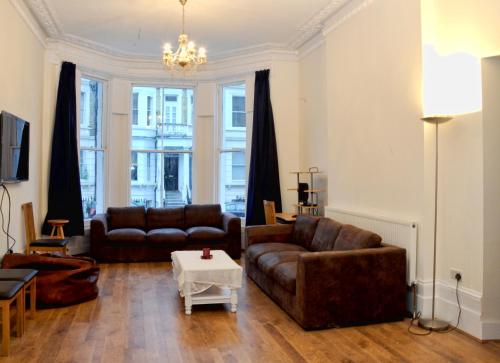 a living room with two leather couches and a table at Saint James Backpackers in London