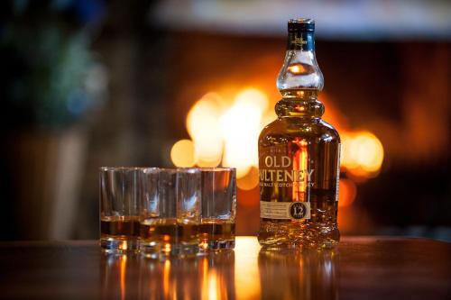 a bottle of alcohol next to two glasses on a table at Loch Ness Lodge Hotel in Drumnadrochit