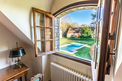 an arched window in a room with a view of a pool at Le Colombier de Hanches - Teritoria in Hanches