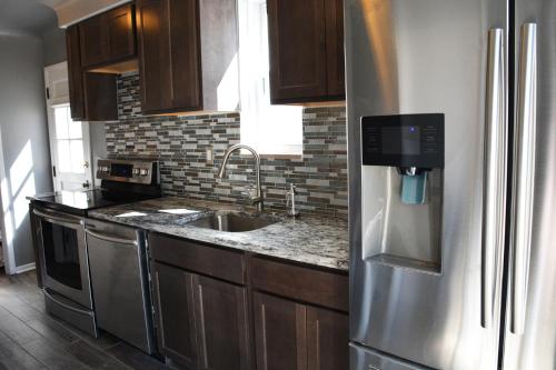 a kitchen with a stainless steel refrigerator and a sink at Stunning Downtown Royal Oak Townhouse (909) in Royal Oak