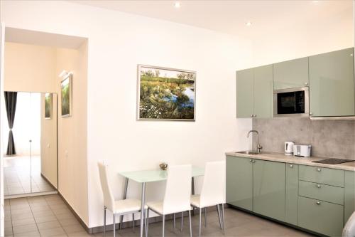 kuchnia z białymi szafkami, stołem i krzesłami w obiekcie Flowers apartments w Pradze