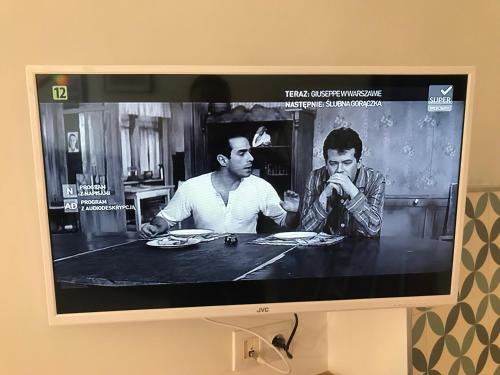 un écran de télévision avec une photo de deux hommes mangeant dans l'établissement Close to Beach 1, à Kołobrzeg