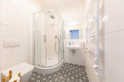 a white bathroom with a shower and a sink at PlayRoom Aparthotel in Krakow