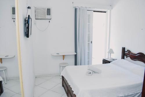 um quarto branco com uma cama e uma janela em Pousada Kopenhagen Beach em Cabo Frio