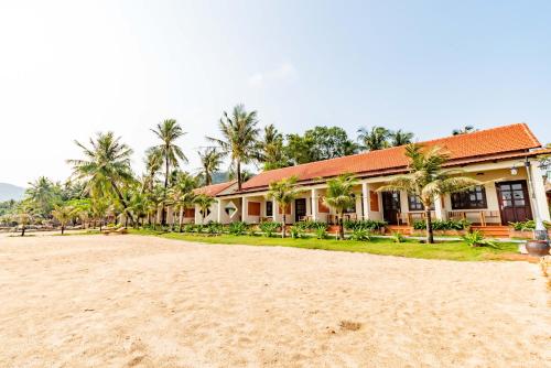a building on the beach with palm trees in the background at Hula Hula Seafront Phu Quoc in Phu Quoc