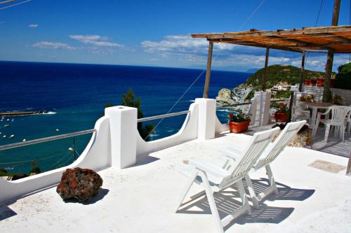 ein Paar weiße Stühle auf einem Felsvorsprung mit Blick auf den Ozean in der Unterkunft Maridea - Vela in Ponza