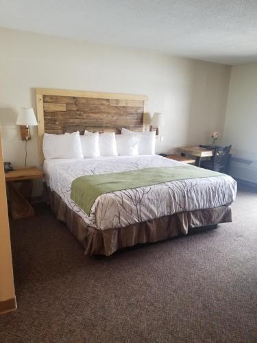een slaapkamer met een groot bed met een houten hoofdeinde bij St. Croix Inn in Solon Springs