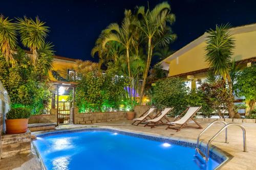 una piscina con tumbonas junto a una casa en Lemuria Apart Hotel, en Florianópolis