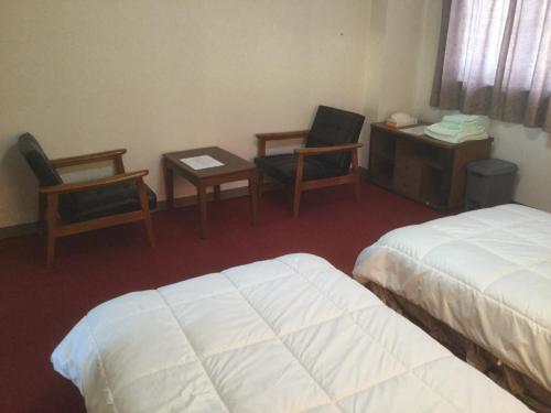 Cette chambre d'hôtel comprend deux lits, une table et des chaises. dans l'établissement Homestay Dream / Vacation STAY 3779, à Uonuma