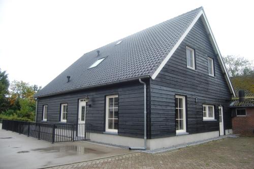 una casa negra con techo de gambrel en Toenders en Wintelre