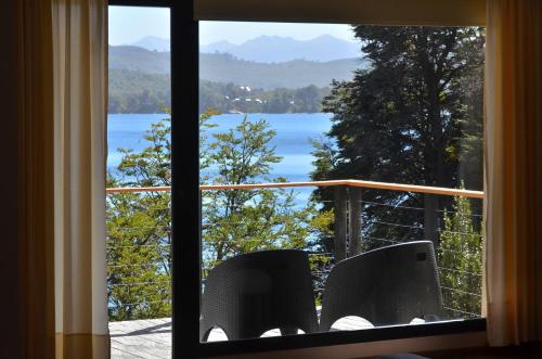 a window with two chairs and a view of a lake at Amarras in Villa Pehuenia