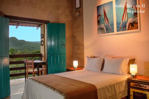 a bedroom with a bed with a green door and a balcony at Casa de Frida Pousada Galeria in Pirenópolis