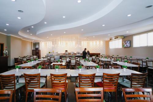 a dining room with white tables and wooden chairs at Grand Hotel Royal Sorocaba by Atlantica in Sorocaba