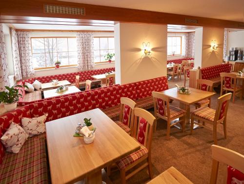 a restaurant with wooden tables and red booths at Lärchenhof in Flachau