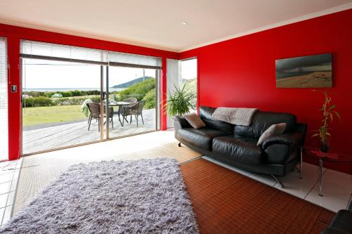 ein Wohnzimmer mit einem Sofa und einer roten Wand in der Unterkunft Sisters Beach Retreat in Sisters Beach