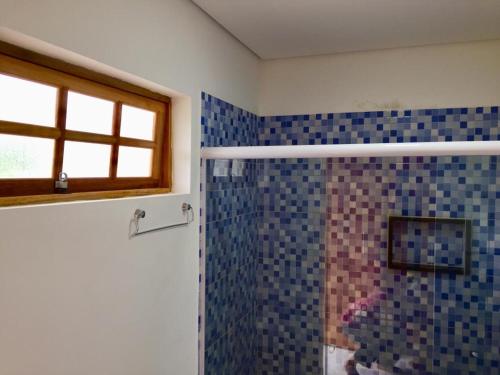 a bathroom with a shower with blue tiles at Sunset Maresias- Casas e Chalés C1 in Maresias
