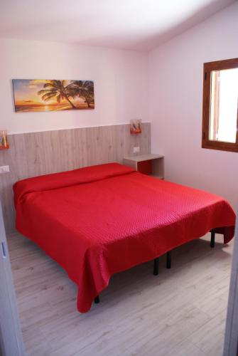 Cama roja en habitación blanca con manta roja en casa mariolu 2 piano mansarda, en Cala Gonone