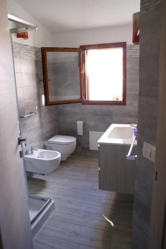 uma casa de banho com um lavatório, um WC e uma janela. em casa mariolu 2 piano mansarda em Cala Gonone