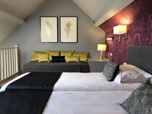 two beds in a bedroom with purple and yellow at Hotel Les Suites - Domaine de Crécy in Crecy la Chapelle