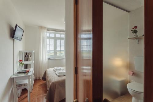 a bathroom with a bed and a toilet in a room at Conde Távora in Atouguia da Baleia