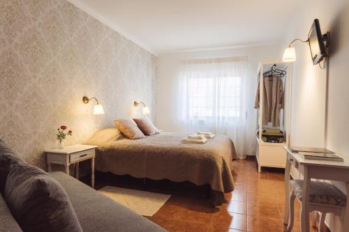 um quarto com uma cama, um sofá e uma janela em YEY Atouguia da Baleia em Peniche