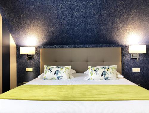 a bedroom with a bed with two lamps on the wall at Hotel Les Suites - Domaine de Crécy in Crecy la Chapelle