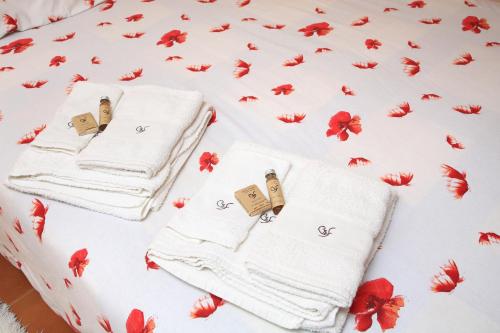 a bed with white towels and red flowers on it at Casa S. Félix in Arcos