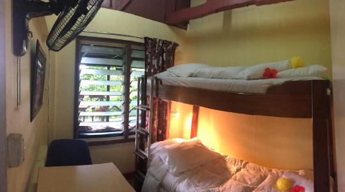 two bunk beds in a room with a table and a window at Treetops Boutique Hotel & Bungalows in Port Vila