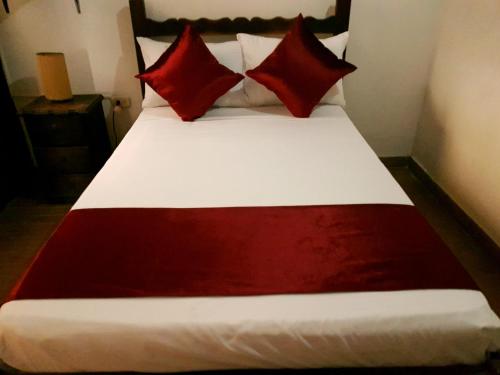 a bed with red and white pillows on it at Hotel Don Juan Colonial in Floridablanca